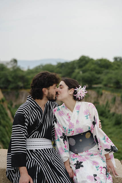 Couple wearing traditional Japanese yukata robes sharing a kiss outdoors