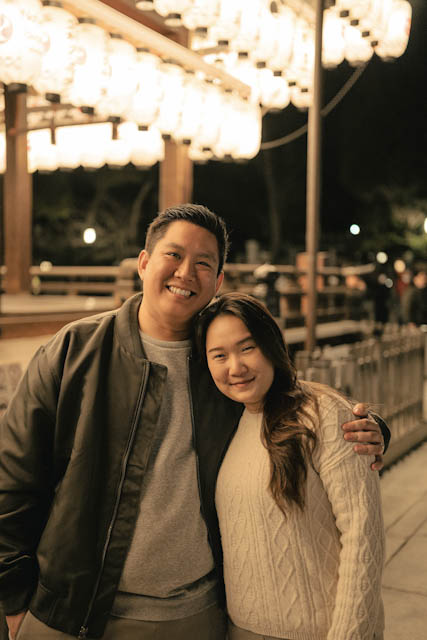 Smiling couple standing together at night under rows of glowing paper lanterns