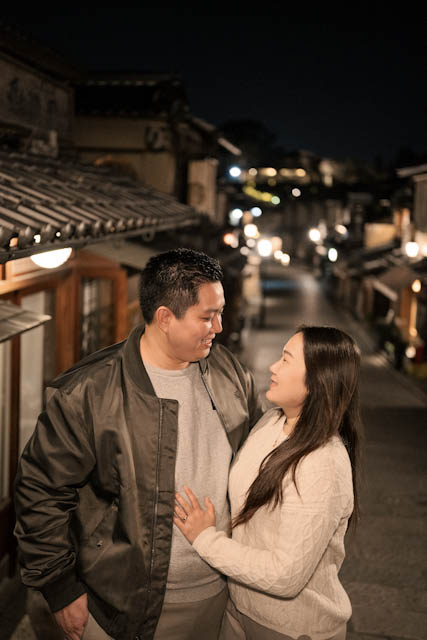 Couple standing close together on a dimly lit street at night