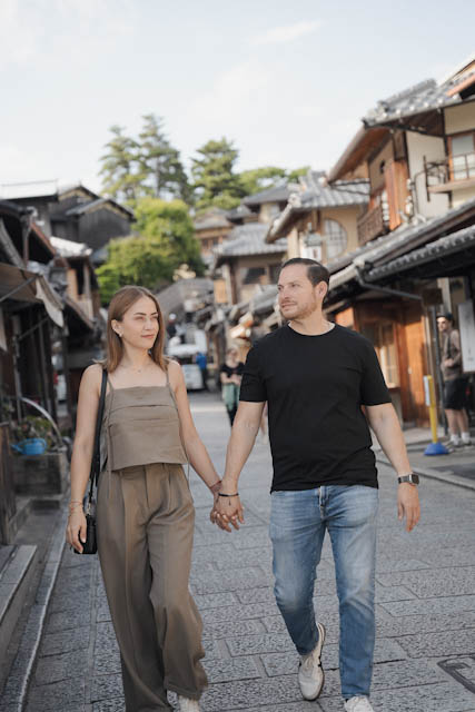 Couple holding hands walking down traditional street with wooden buildings