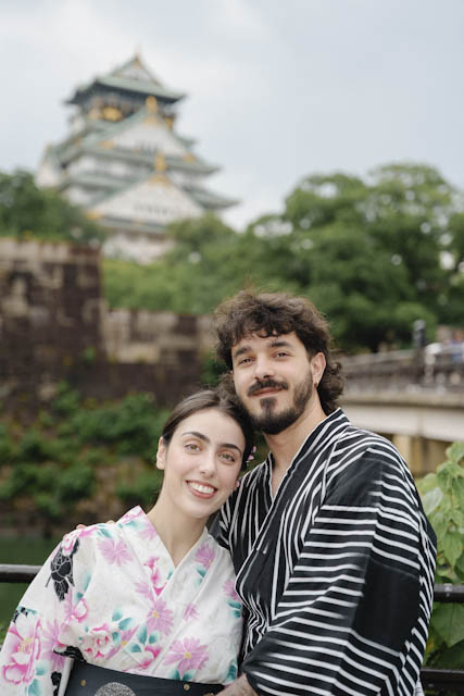 Couple in traditional yukata smiling together with a castle in the background