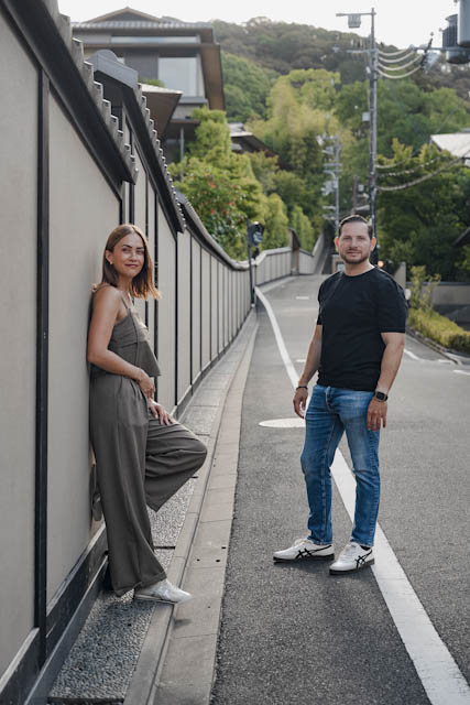 Couple posing on a road near a traditional Japanese wall and greenery