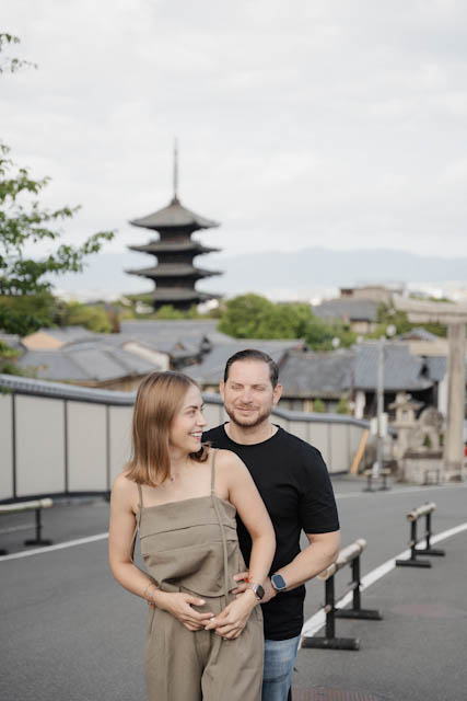 Couple standing together outdoors with a traditional Japanese pagoda in the background.