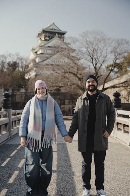 Couple holding hands on bridge with Osaka Castle background