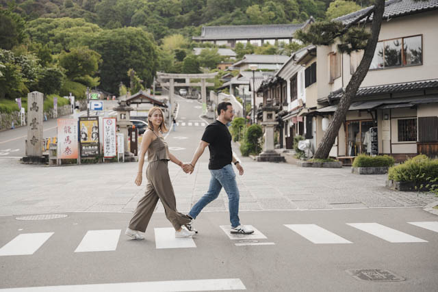 Couple holding hands walking across crosswalk in traditional Japanese town
