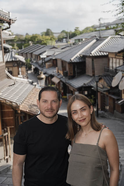 Couple posing on a street with traditional Japanese tiled roofs in background
