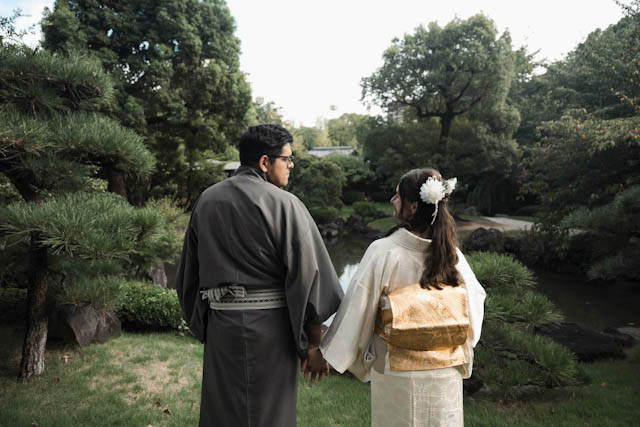 Couple in traditional Japanese wedding kimono holding hands in a garden