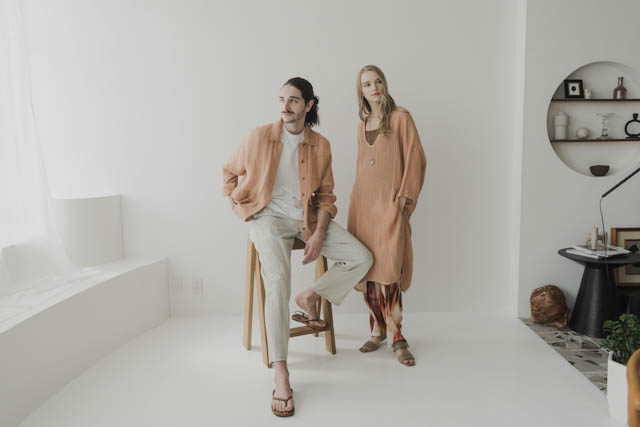 Male and female models wearing earth-toned linen outfits posing in a minimalist white studio
