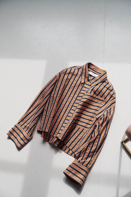 A striped orange and navy shirt lying flat on a white surface.