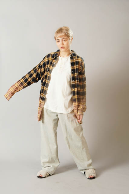 Model wearing yellow plaid shirt, white tee, and furry sandals