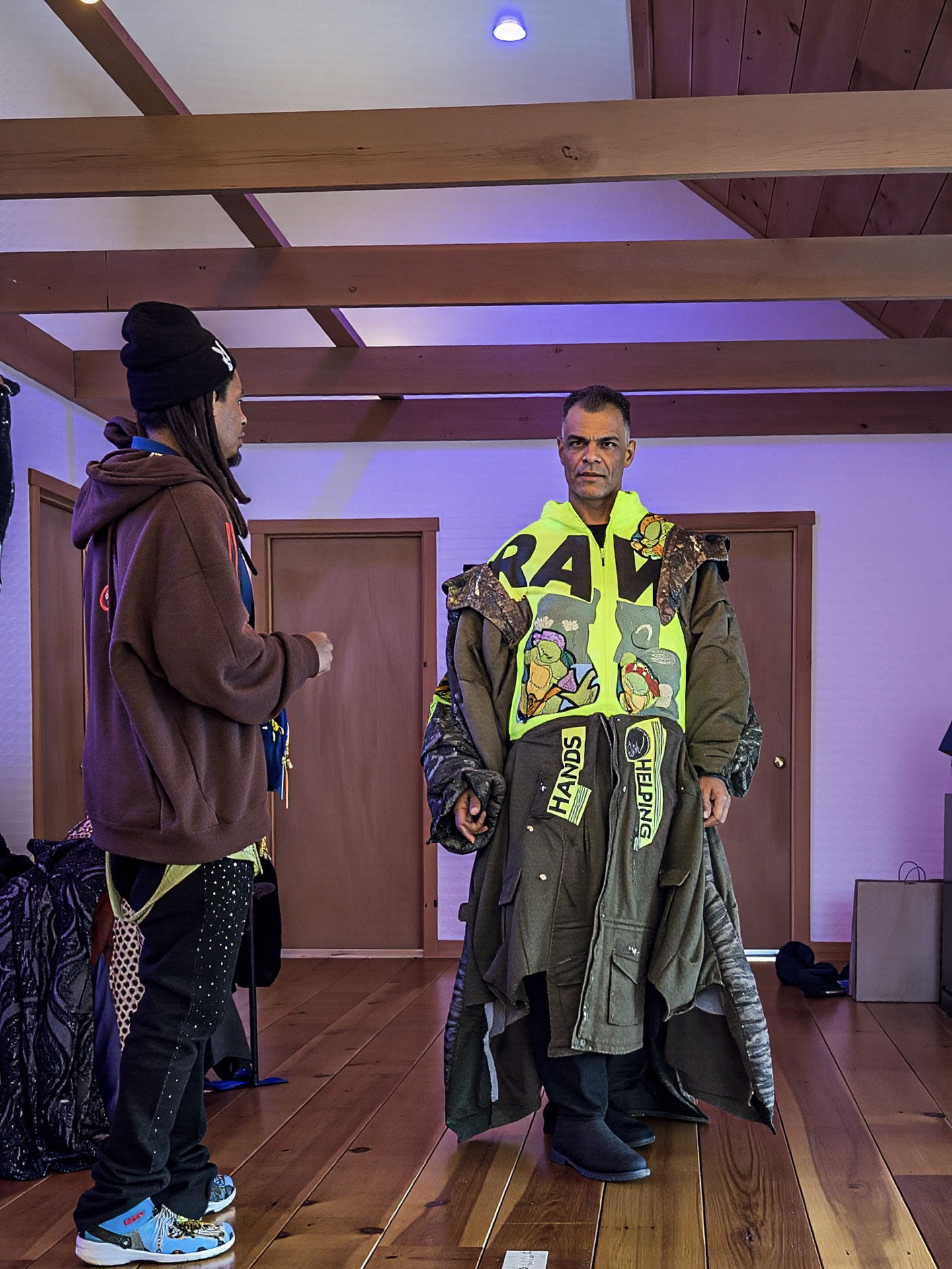 Two people discussing a bright graphic garment in a studio.