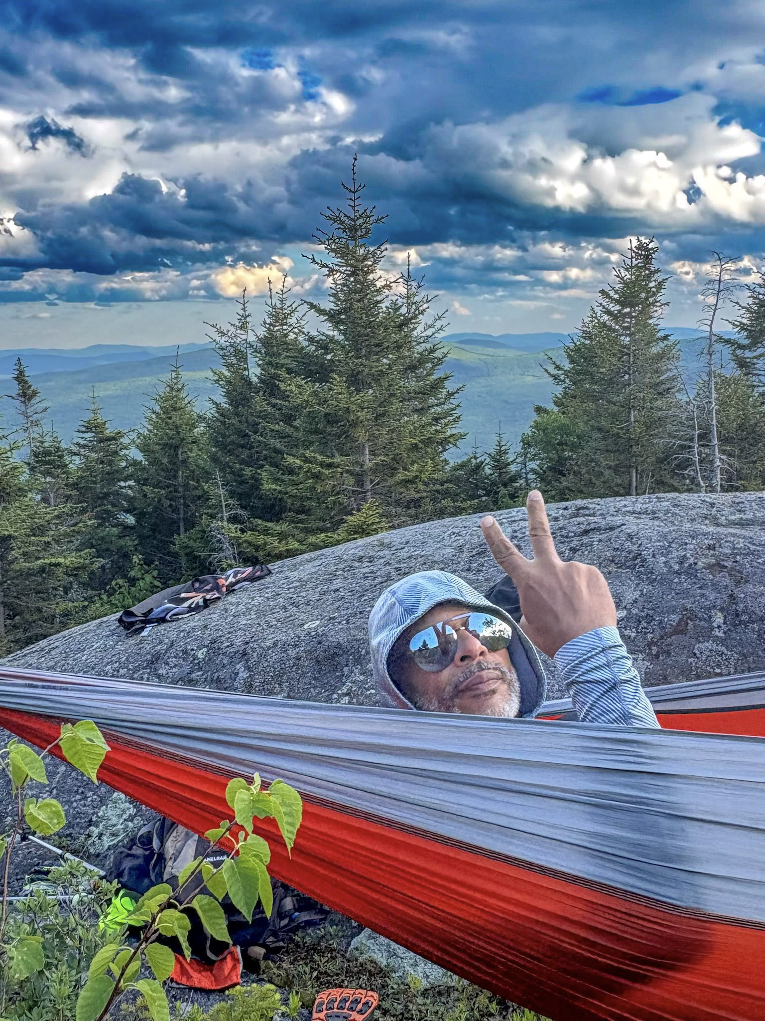 Kristopher resting in a hammock beside a mountain view.