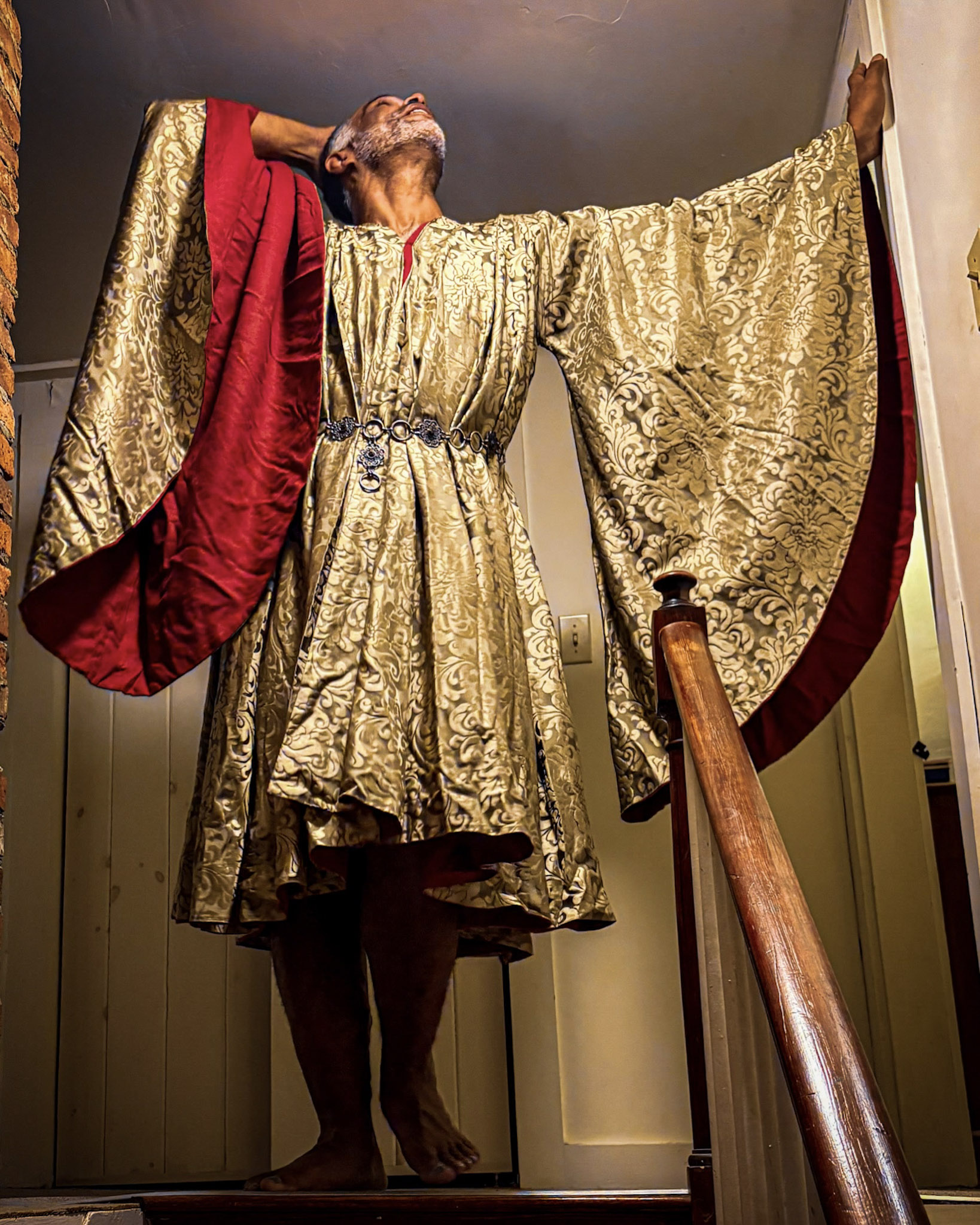Kristopher wearing a wide-sleeved gold robe and red sash.