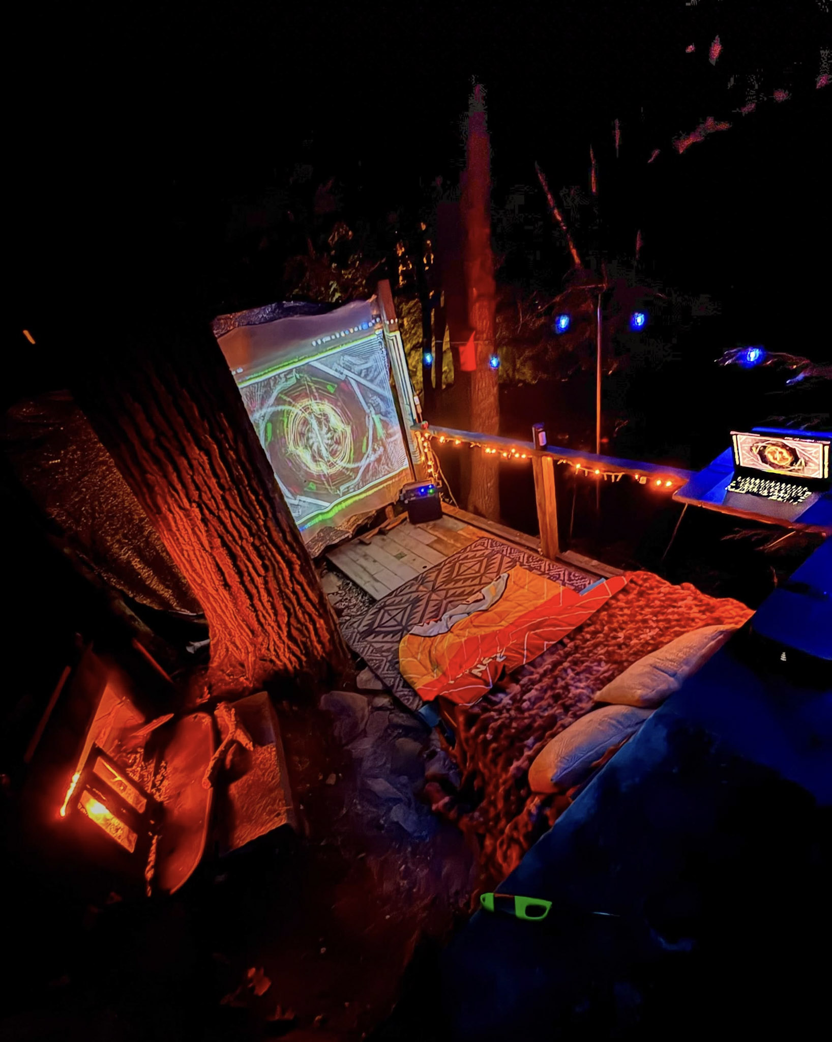 Dim outdoor space with textiles, colored lighting and trees.