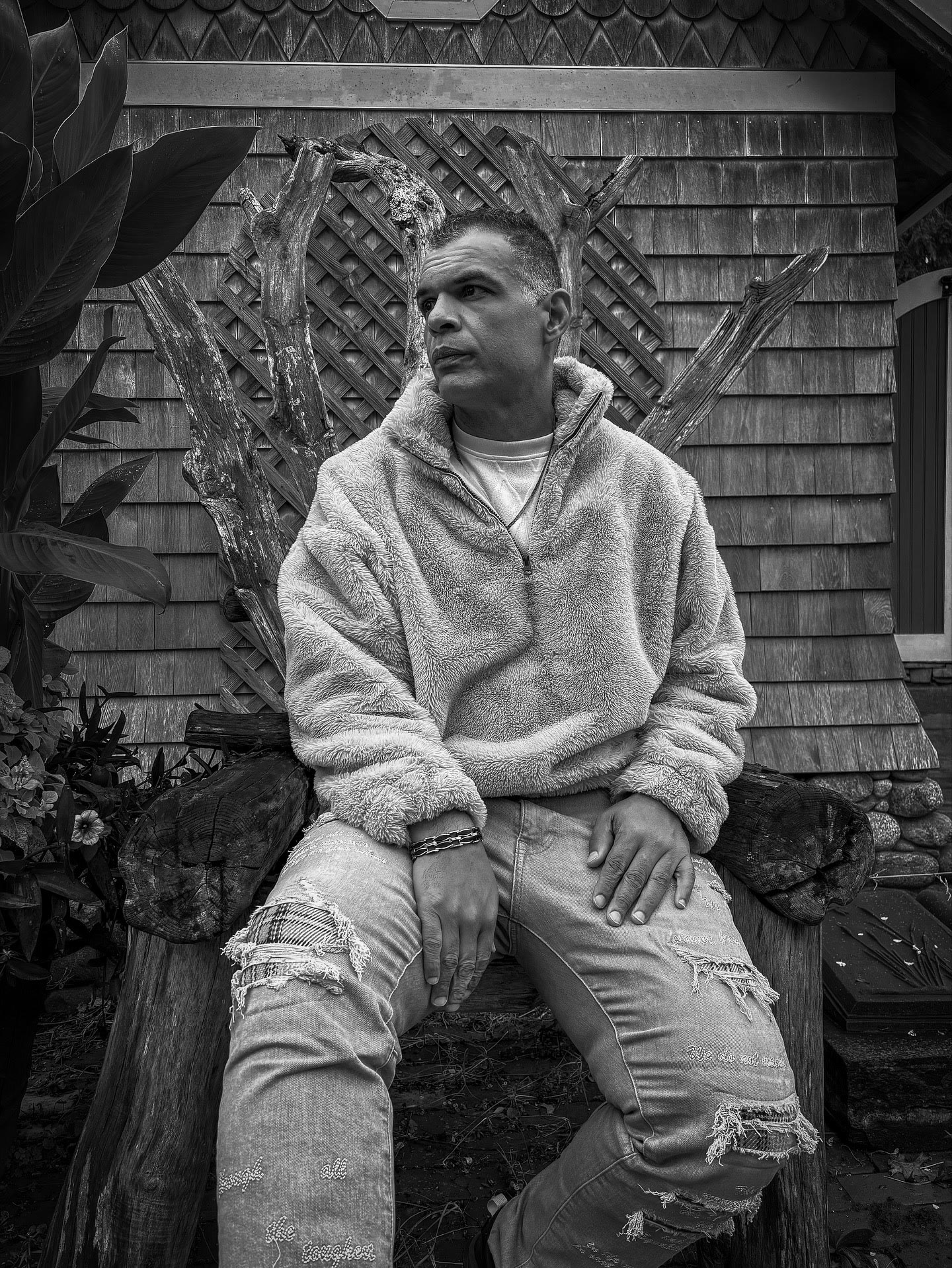 Black-and-white portrait of Kristopher in a hoodie beside stonework.