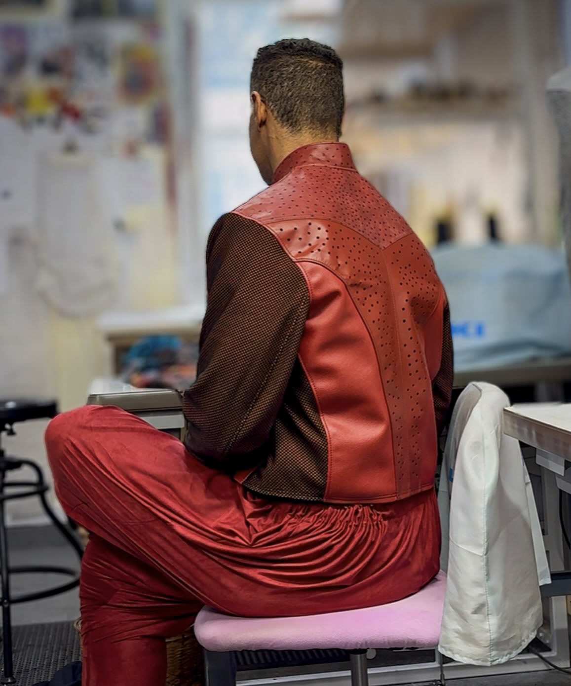 Back view of Kristopher wearing red leather garments in a studio.