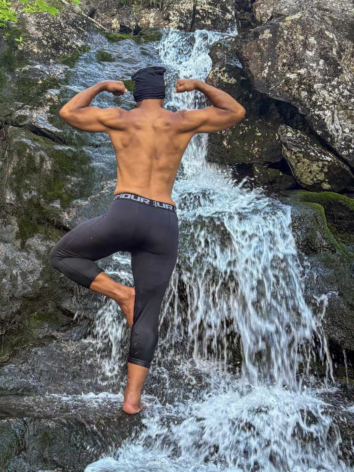 Kristopher standing with his back to the camera beside a waterfall.