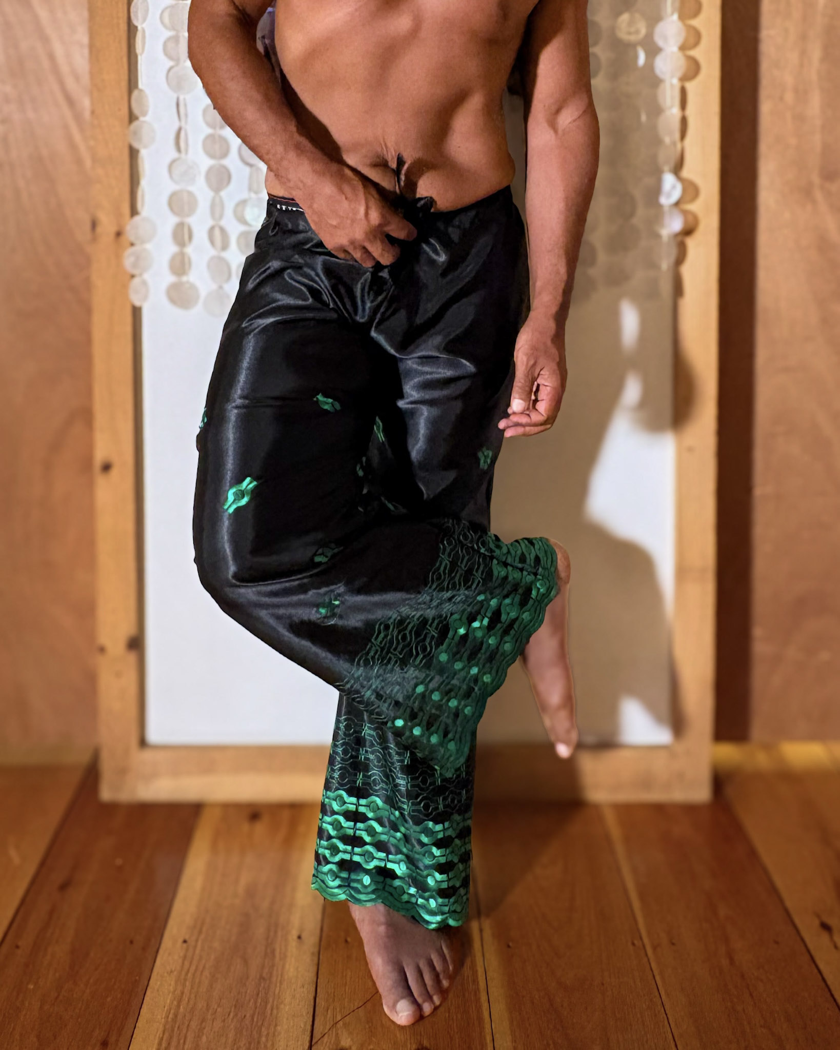Kristopher wearing handmade black satin trousers with green patterned lower legs.