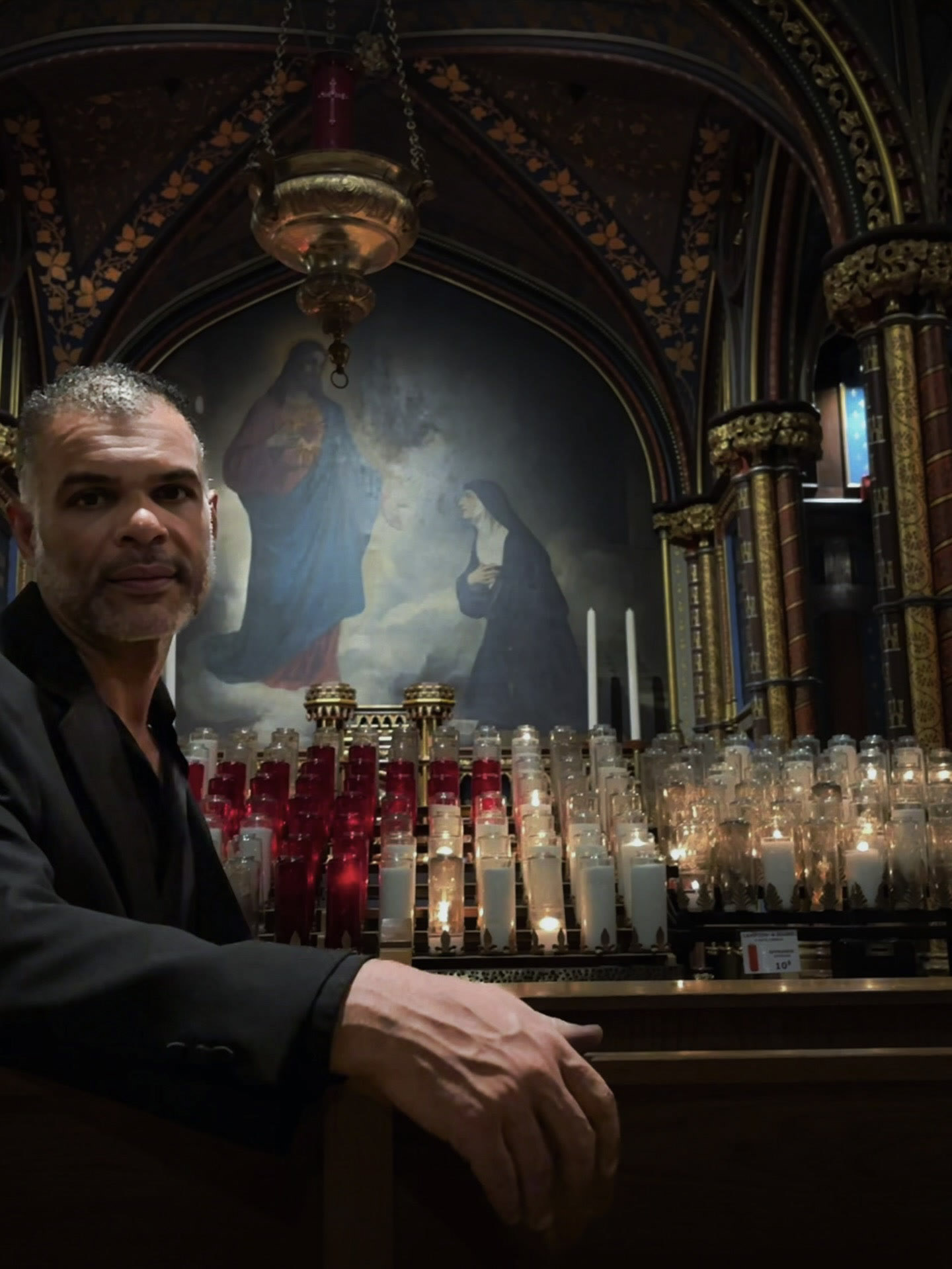 Kristopher seated in a dark shirt inside an ornate historic interior.