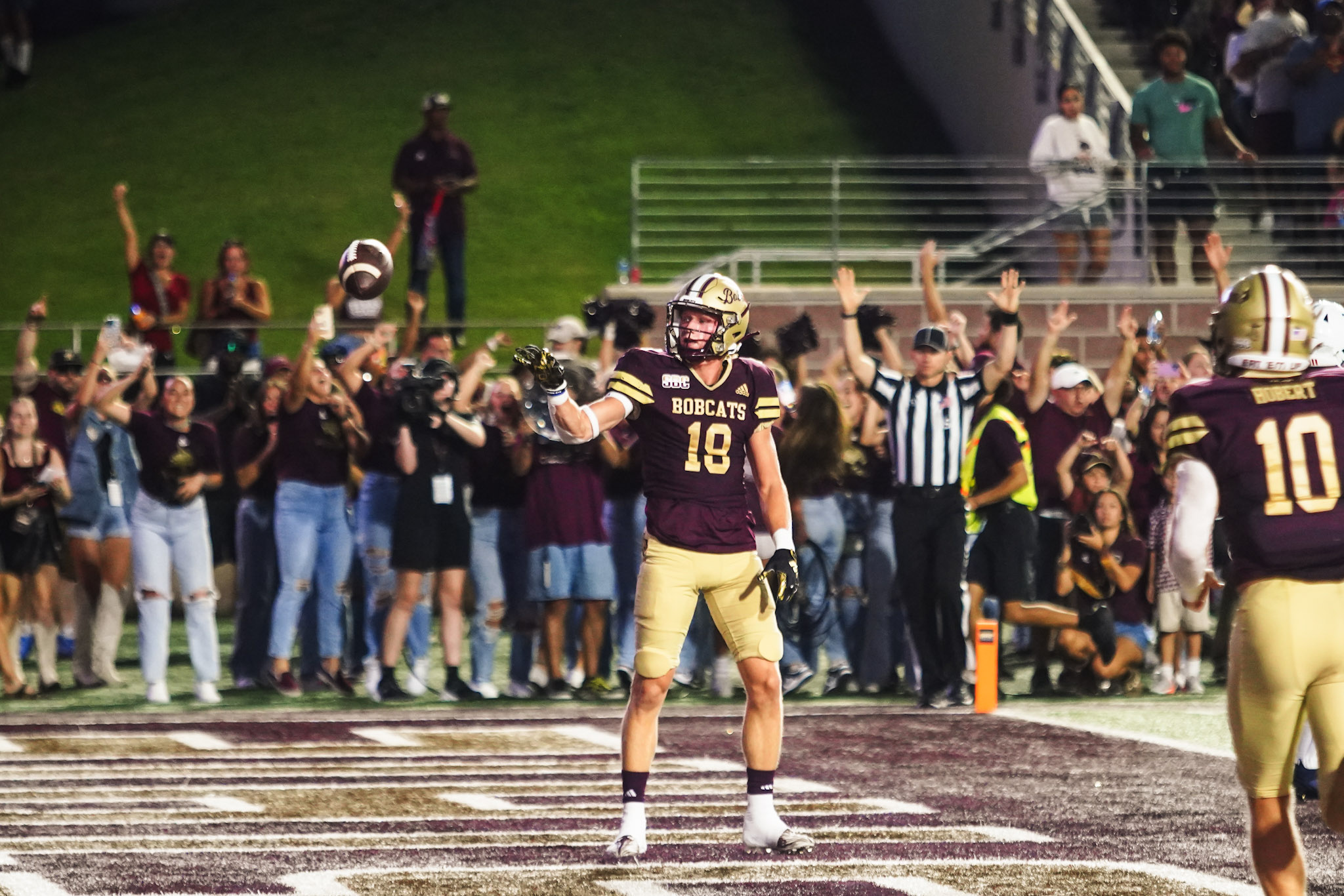 Bobcats wide receiver in maroon and gold (18) celebrates a touchdown