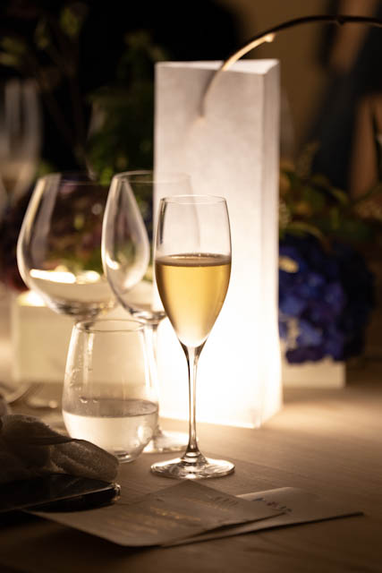 Glass of white wine on a wooden table with a glowing lantern centerpiece