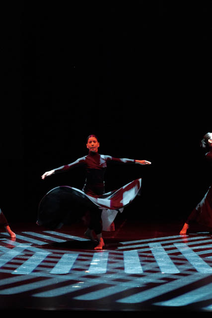 Dancer performing on stage with dramatic lighting and floor projections